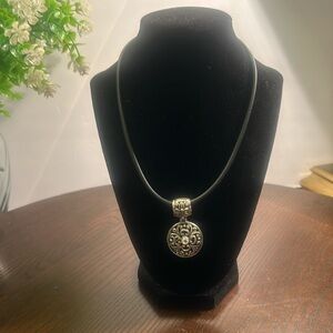 Circular silver tone pendant w/ center rhinestone on black cord w/ lobster clasp